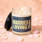 Glass candle with lit wick and "MARRIED & LOVING IT" text on label.