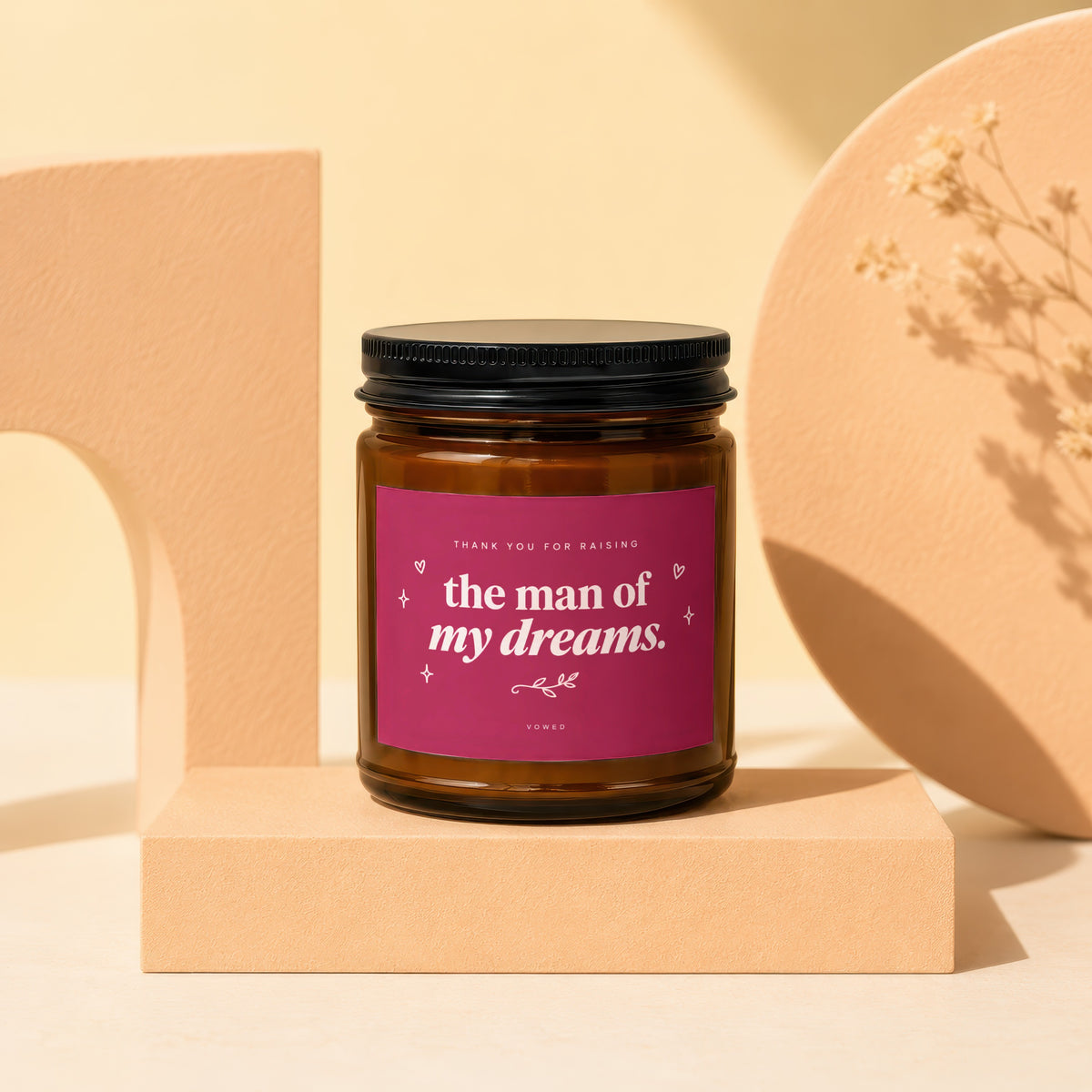 Glass candle with black lid, pink label reads "the man of my dreams."