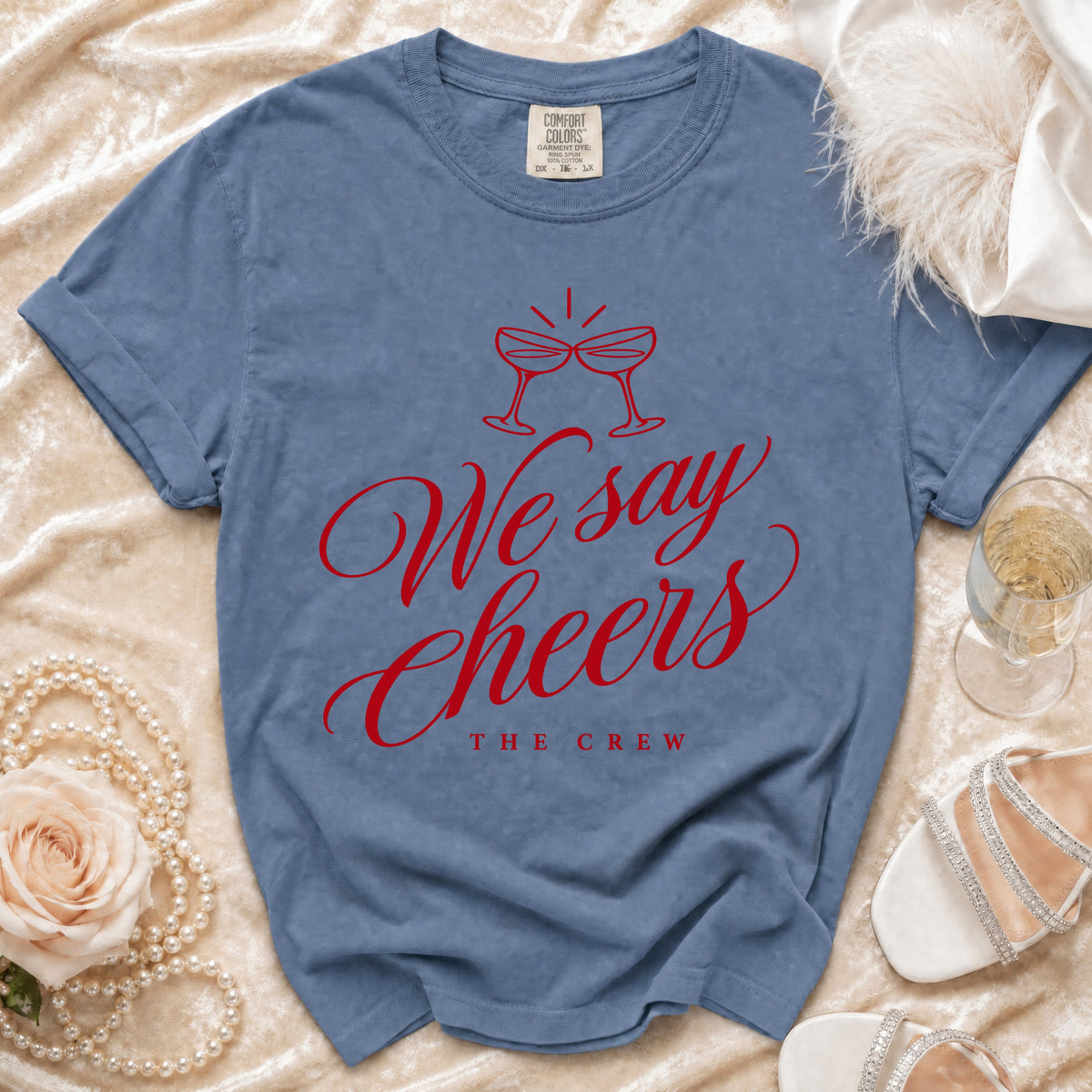 Blue t-shirt with red text "We say Cheers THE CREW" and champagne glasses graphic.