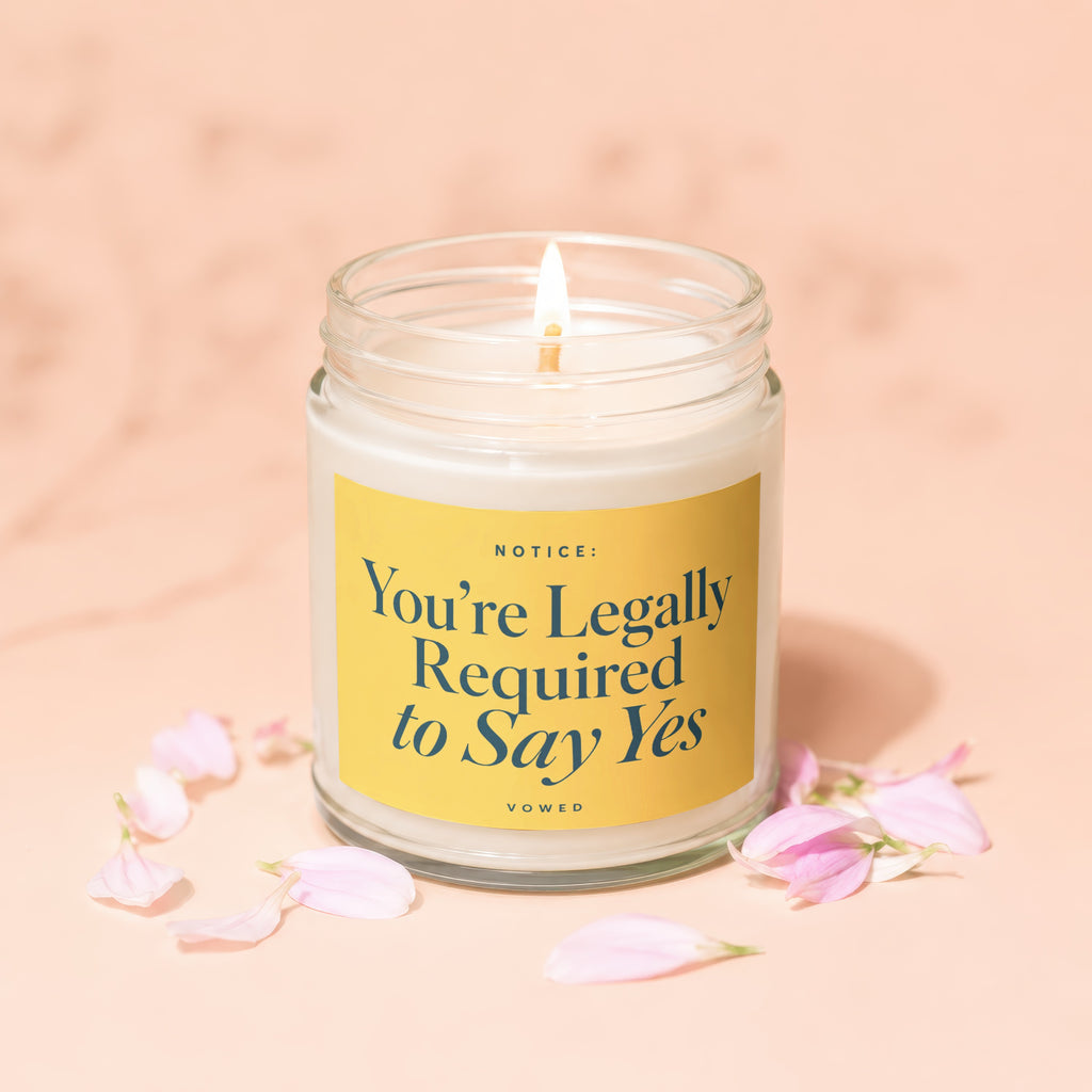 Glass jar candle with yellow label reading "Notice: You're Legally Required to Say Yes".