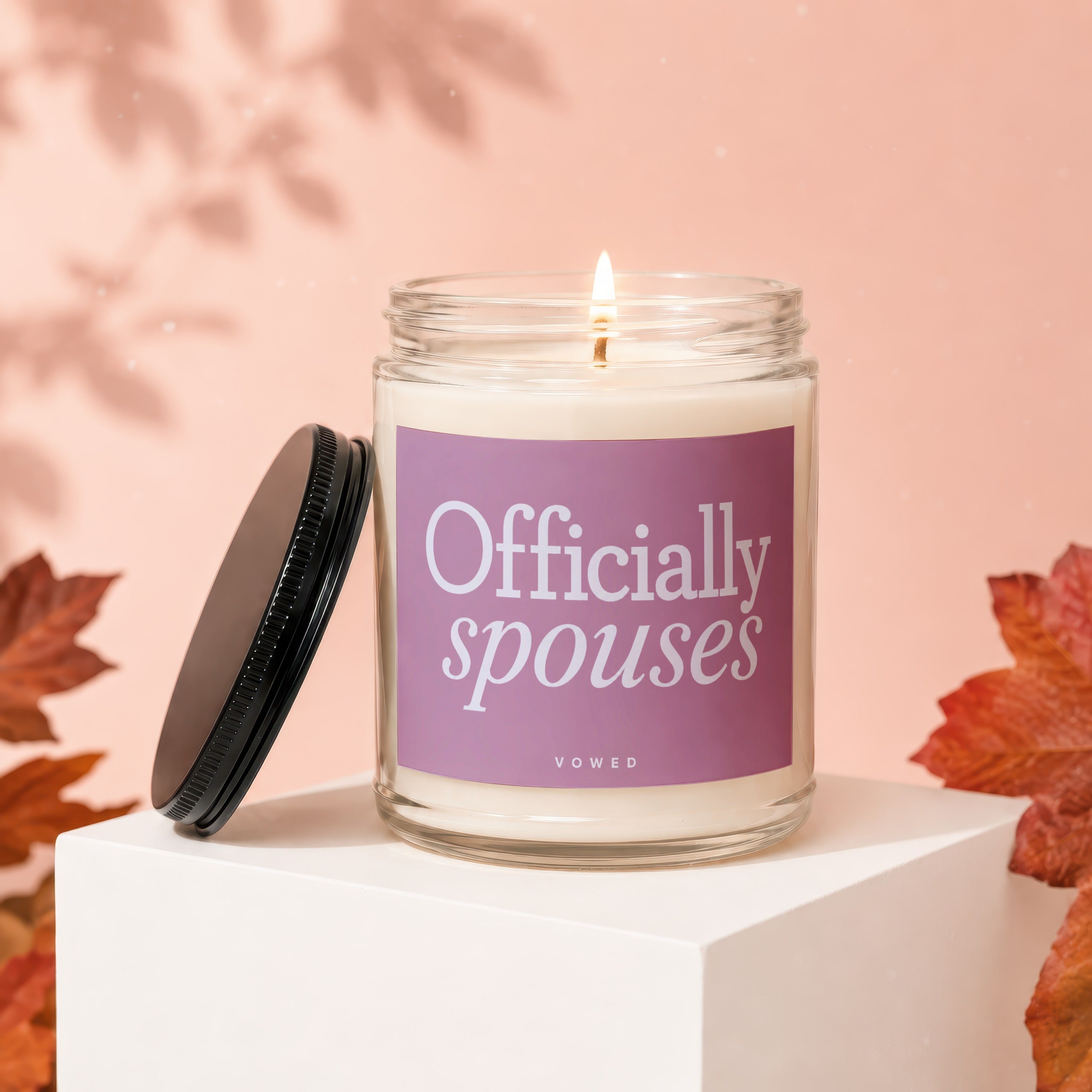 Candle with a lit wick and a lavender label that reads "Officially spouses."