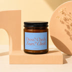Amber jar candle with blue label reading "Dress? Check. Tears? Check. VOWED."