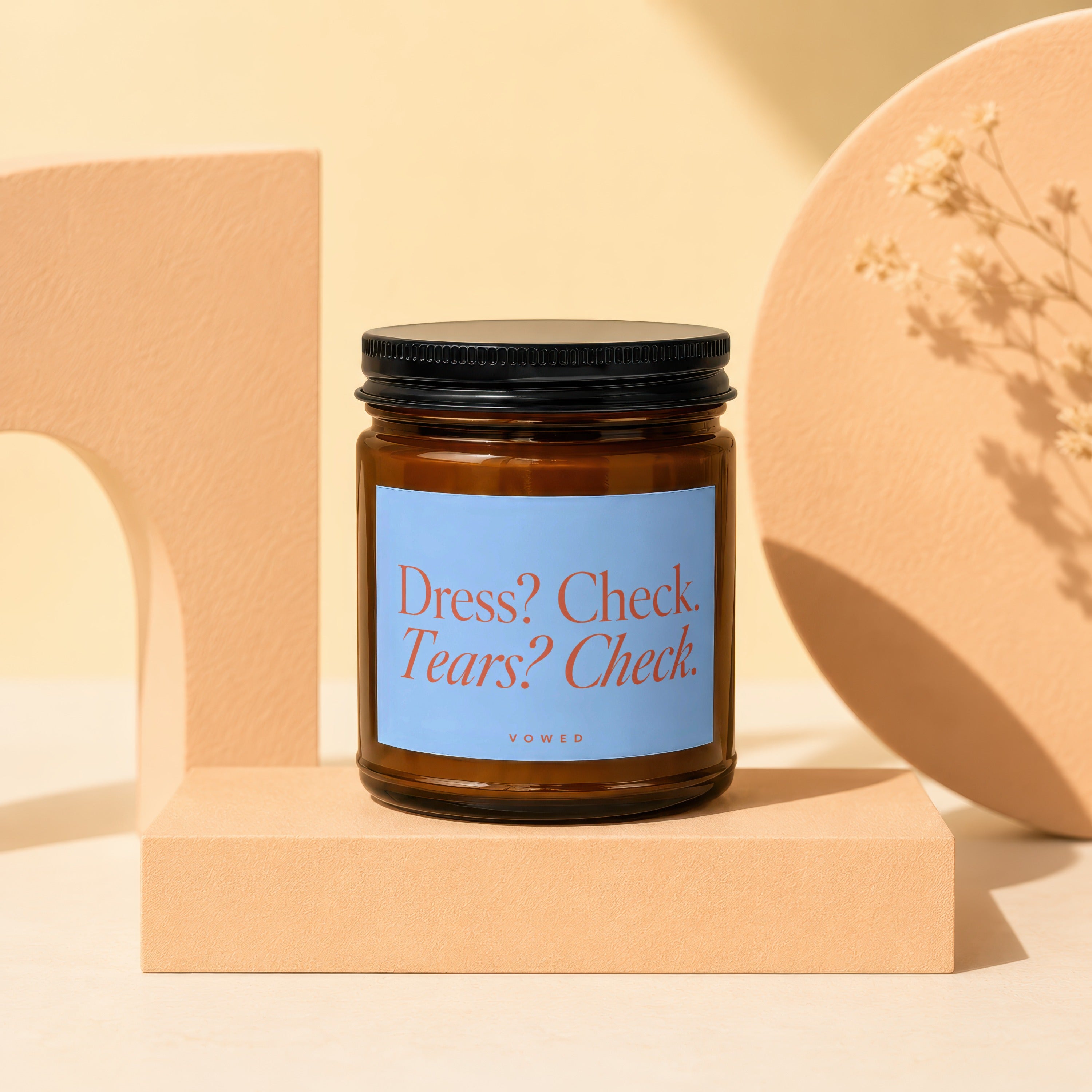 Amber jar candle with blue label reading "Dress? Check. Tears? Check. VOWED."