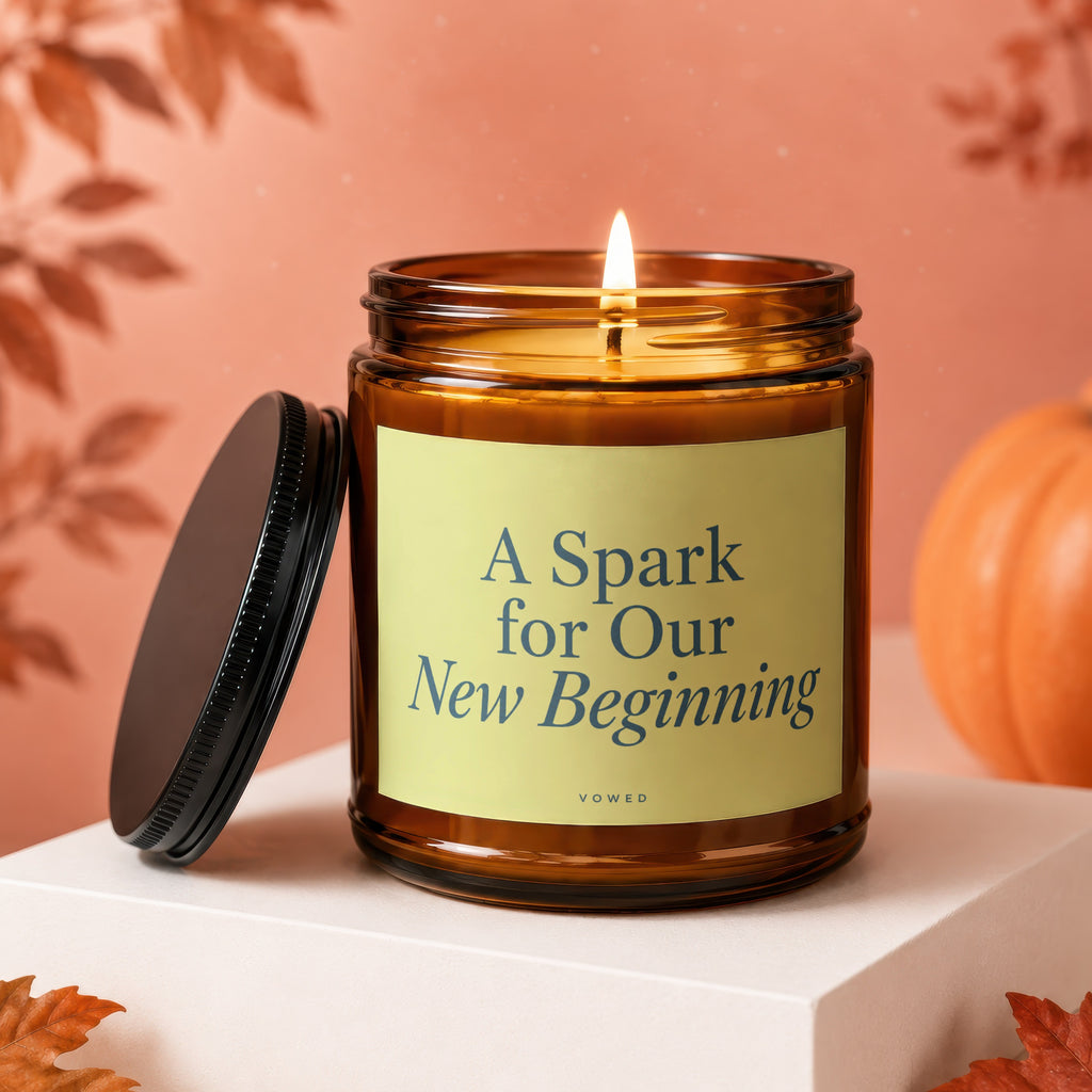 Amber candle with lid off, reading "A Spark for Our New Beginning".