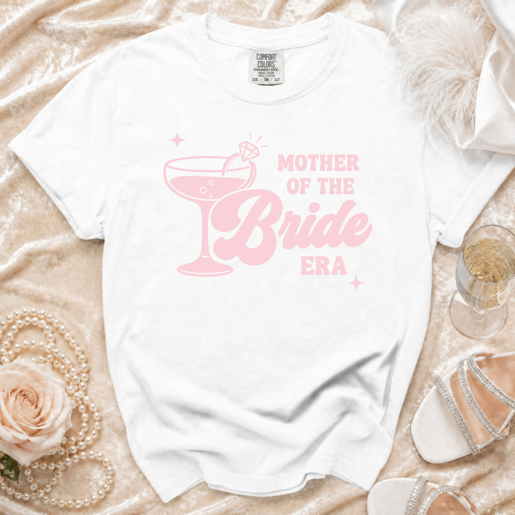 White t-shirt with pink "Mother of the Bride Era" text and a champagne glass graphic.