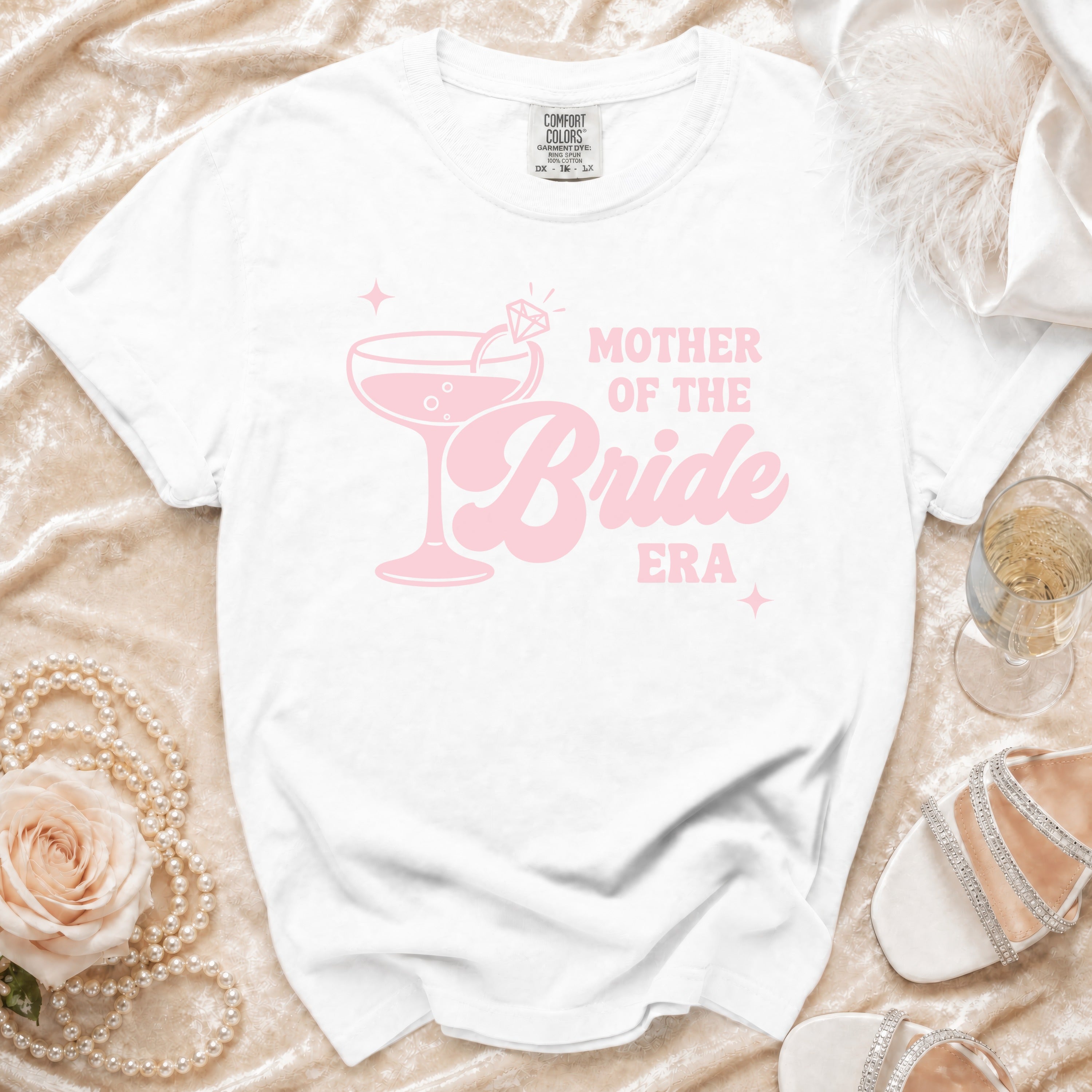White t-shirt with pink "Mother of the Bride Era" text and a champagne glass graphic.