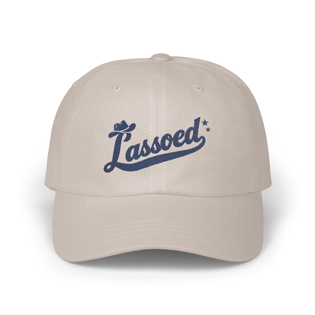 A light gray baseball cap features the blue embroidered script text Lassoed across the front.