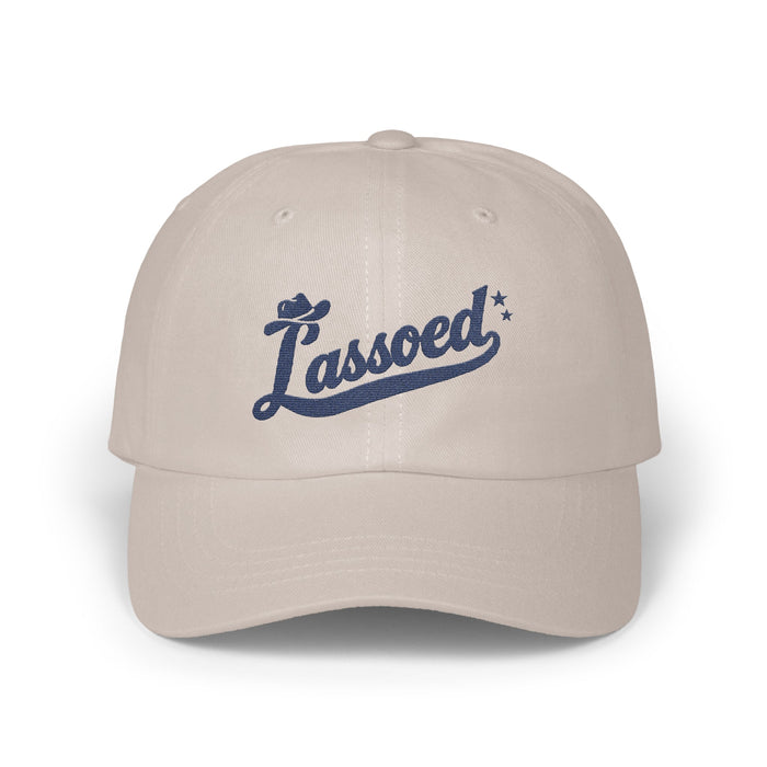 A light gray baseball cap features the blue embroidered script text Lassoed across the front.