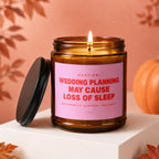 Candle with pink label reading "CAUTION: WEDDING PLANNING MAY CAUSE LOSS OF SLEEP".