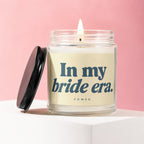 Glass candle with lit wick, lid removed, and text "In my bride era."