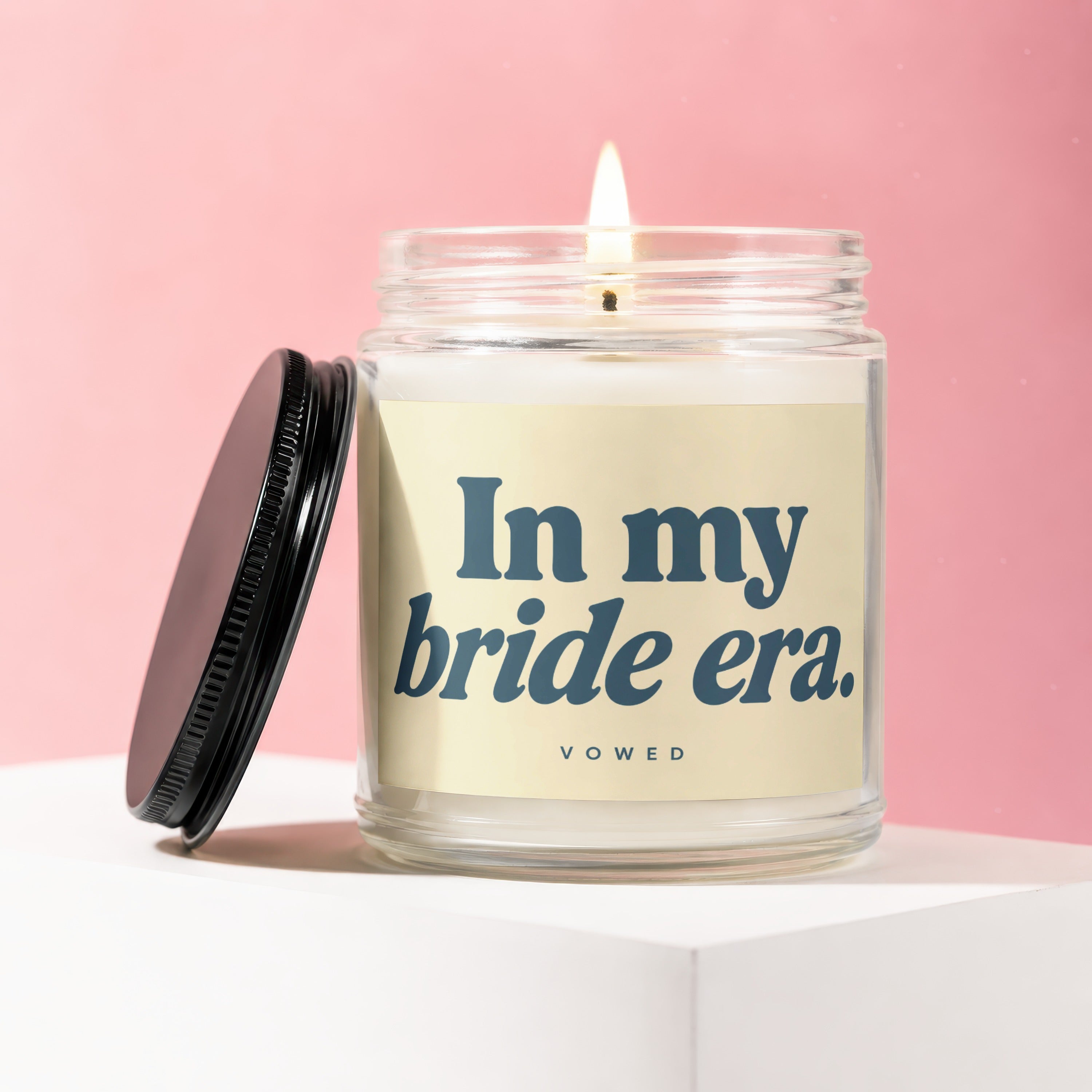 Glass candle with lit wick, lid removed, and text "In my bride era."