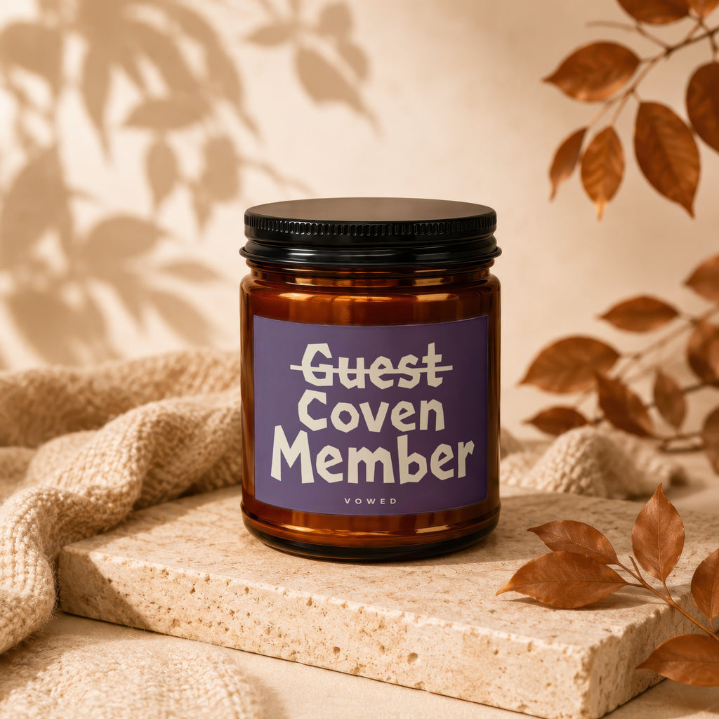Amber jar candle with "Guest Coven Member Vowed" on purple label.