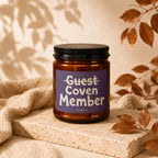 Amber jar candle with "Guest Coven Member Vowed" on purple label.