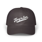 A dark grey baseball cap embroidered with the white script text Tipsy in Love across the front.