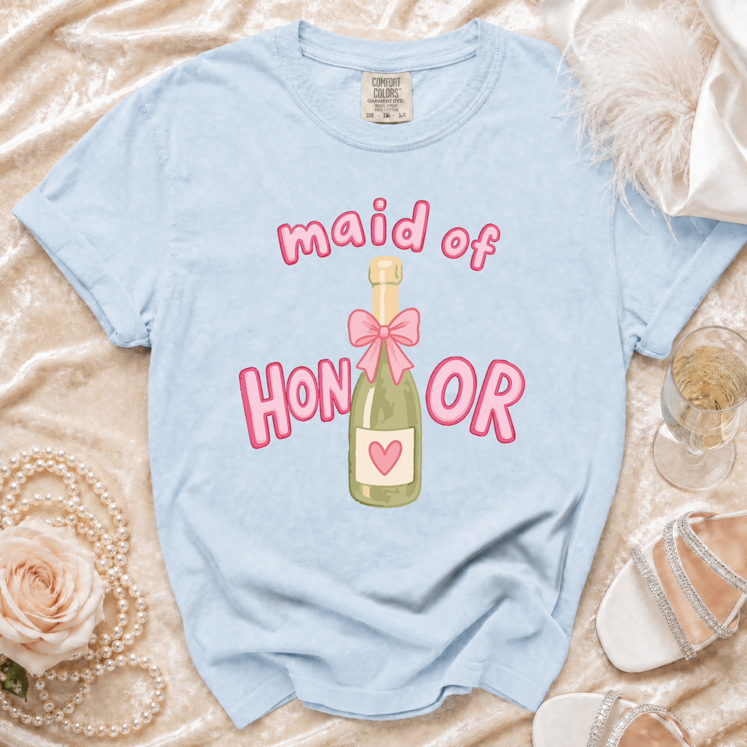 Light blue t-shirt with "maid of HONOR" text and champagne bottle graphic.