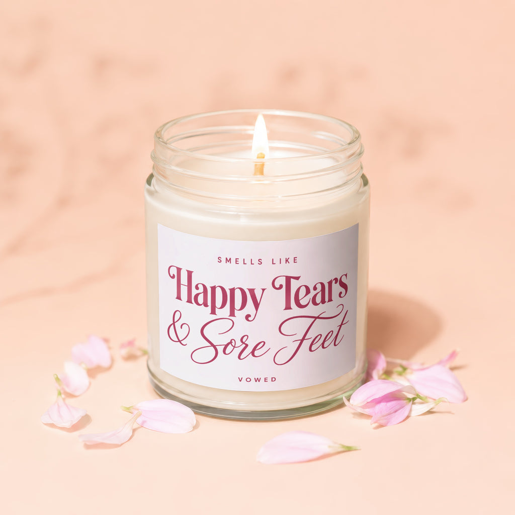 Scented candle in glass jar reading "Smells Like Happy Tears & Sore Feet VOWED".
