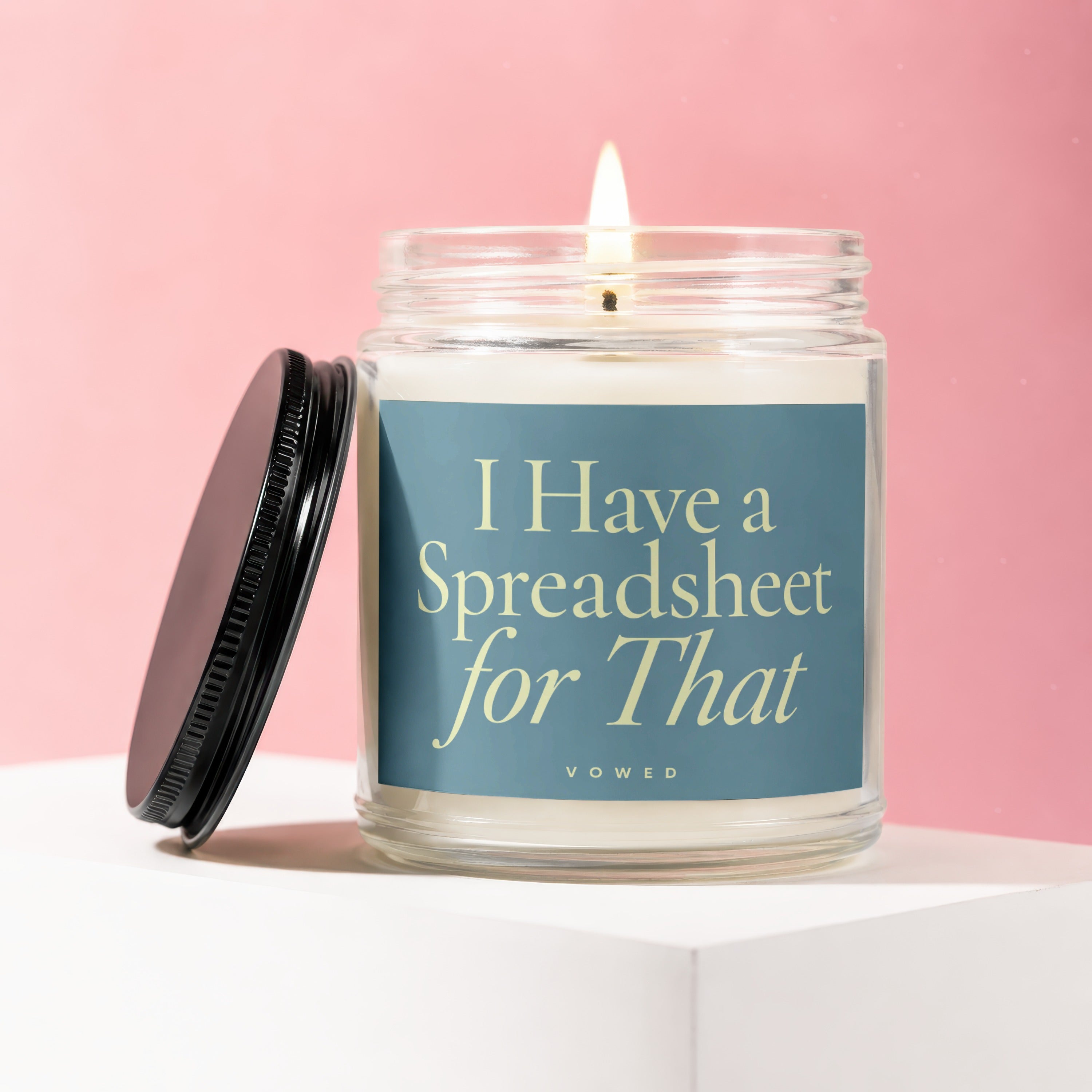 Glass candle with lit wick on white block, black lid next to it. Text: "I Have a Spreadsheet for That".
