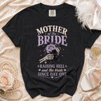 Black t-shirt featuring Mother of the Bride text, a skeleton hand holding roses, and the phrase Raising Hell and the Bride Since Day One.