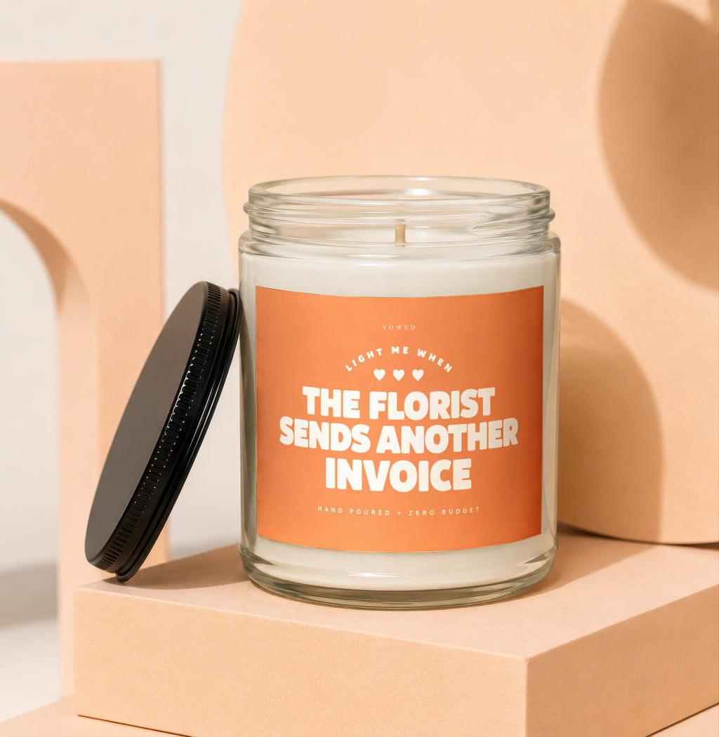 Candle with orange label reading "The Florist Sends Another Invoice."
