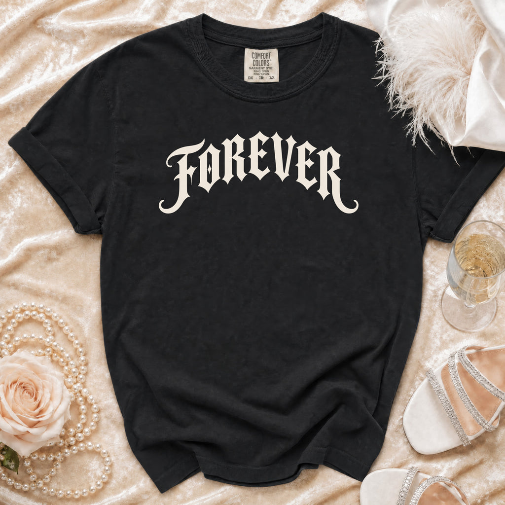 Black t-shirt with "FOREVER" in gothic font, laid out with pearls, rose, and shoes.