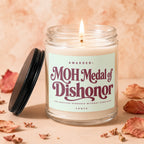 Glass jar candle with "MOH Medal of Dishonor" label and lit wick.