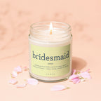 Candle with "bridesmaid" definition on label, surrounded by pink petals.