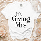 White t-shirt with bold black text reading "It's Giving Mrs".