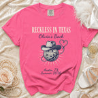 Hot pink t-shirt with "Reckless in Texas Olivia's Bach Austin, TX Summer 2026" and disco ball.