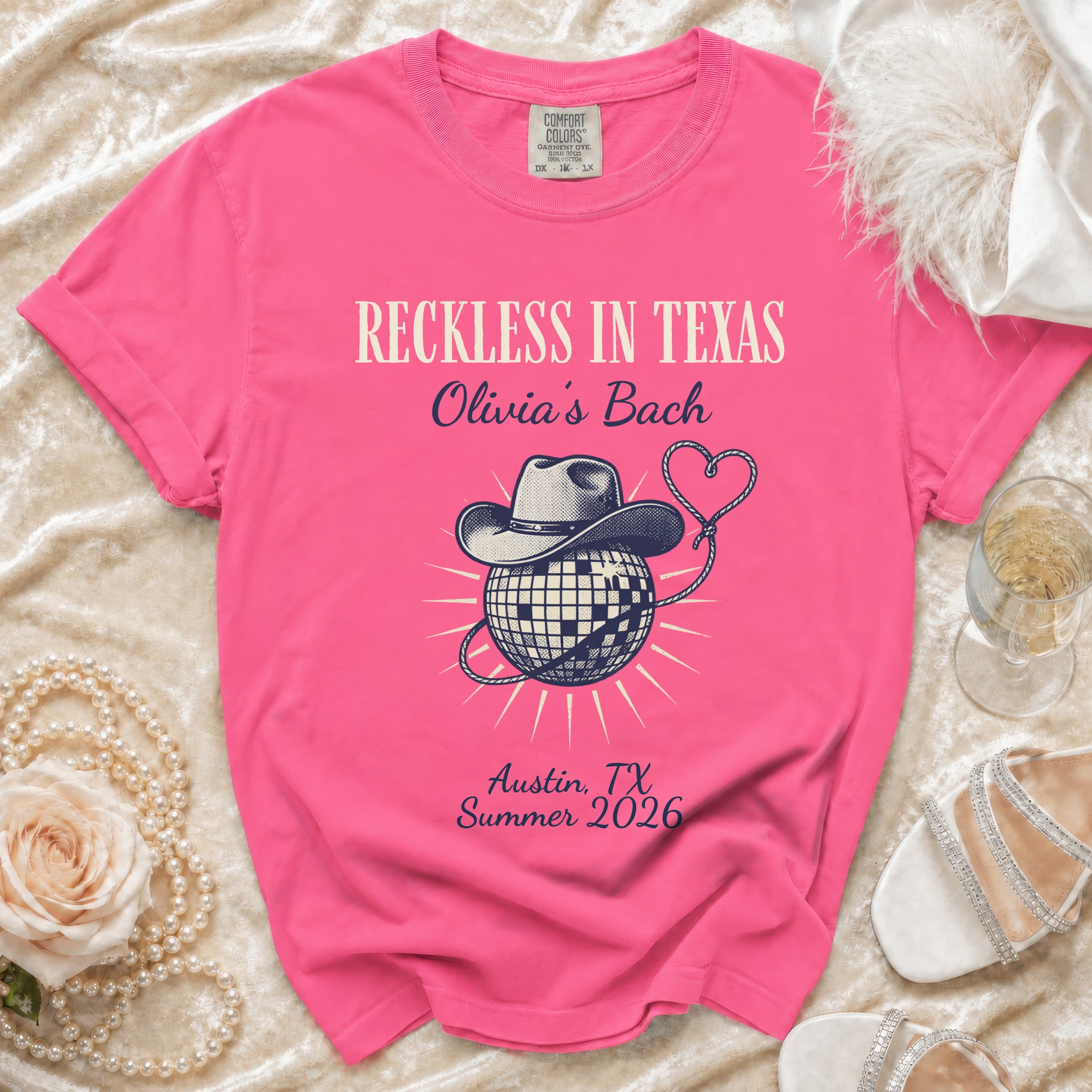 Hot pink t-shirt with "Reckless in Texas Olivia's Bach Austin, TX Summer 2026" and disco ball.