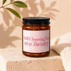 Amber jar candle with pink text that reads "Still Choosing You on a Tuesday".