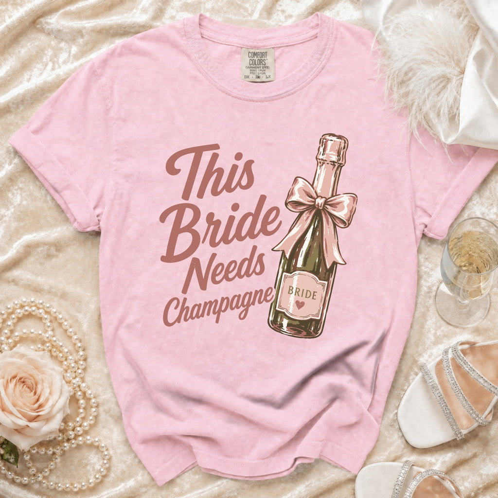 Pink t-shirt with "This Bride Needs Champagne" text and champagne bottle graphic.