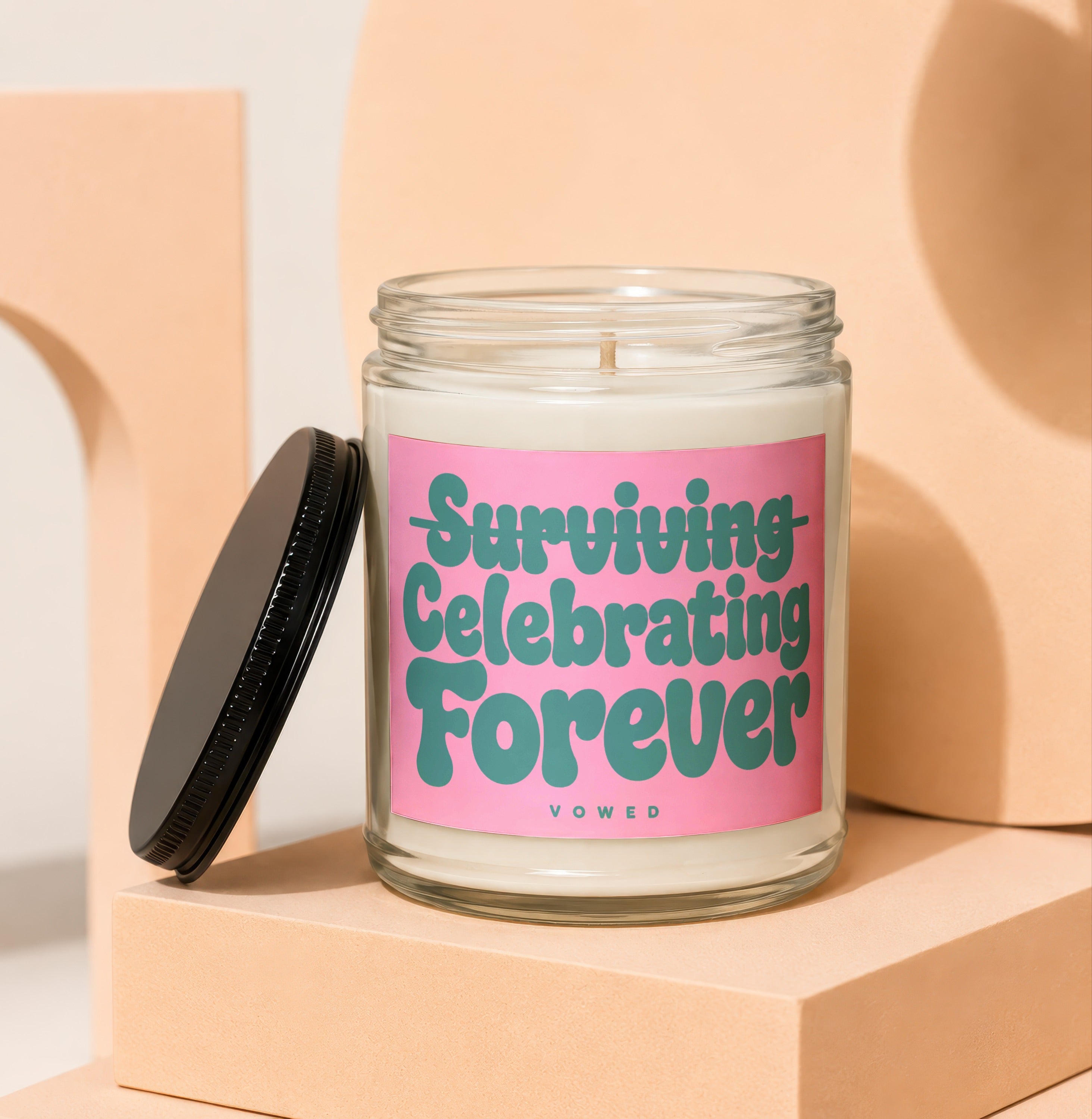 Glass candle with pink label reading "Surviving Celebrating Forever" above "vowed".