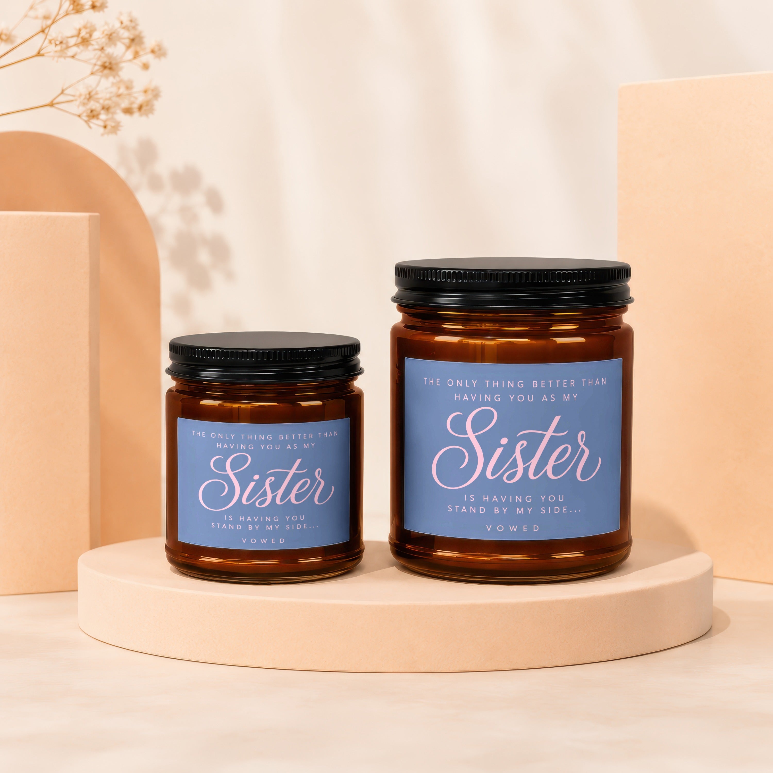Two amber glass candles with black lids, one larger than the other, labeled "Sister".