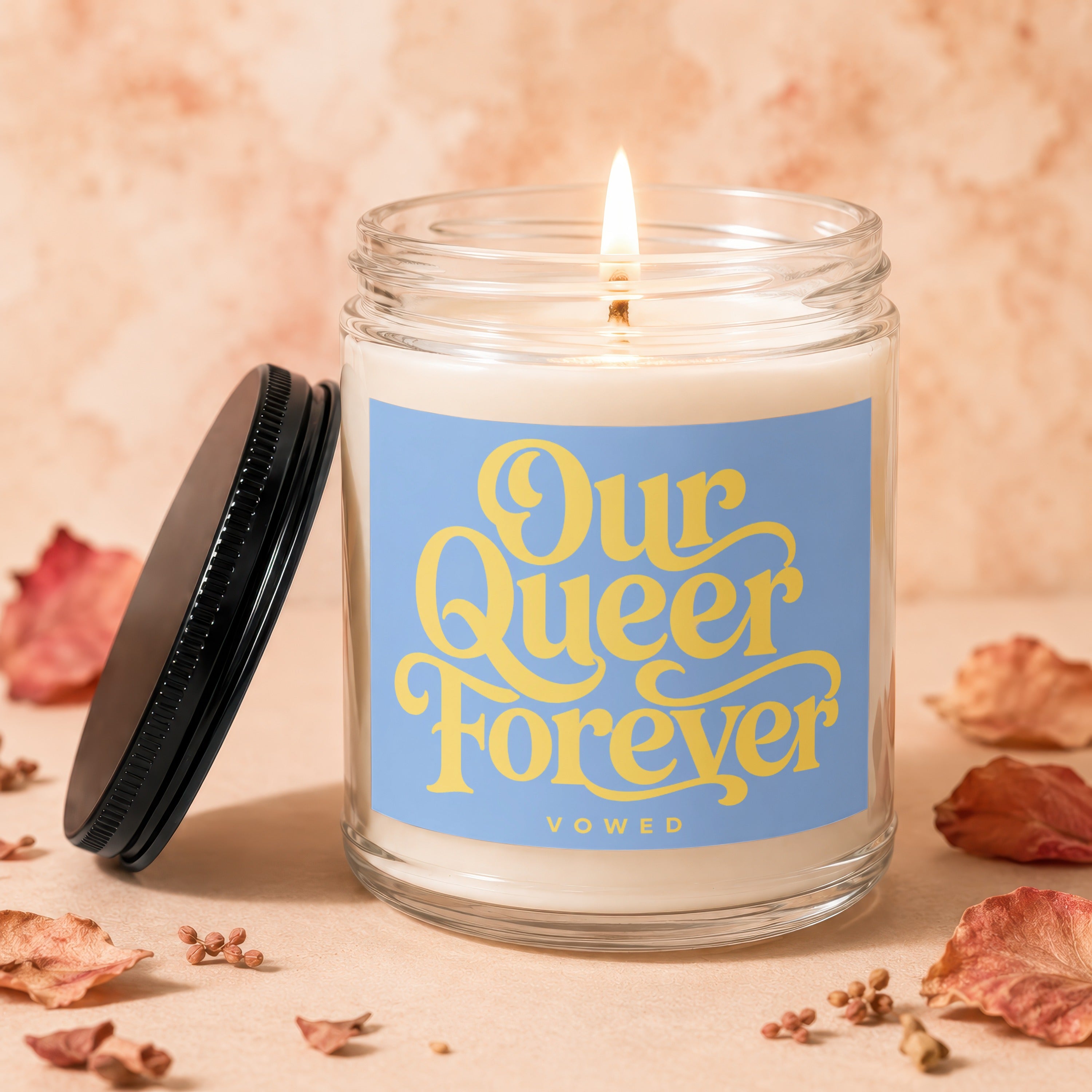 Jar candle with lit flame and label "Our Queer Forever".