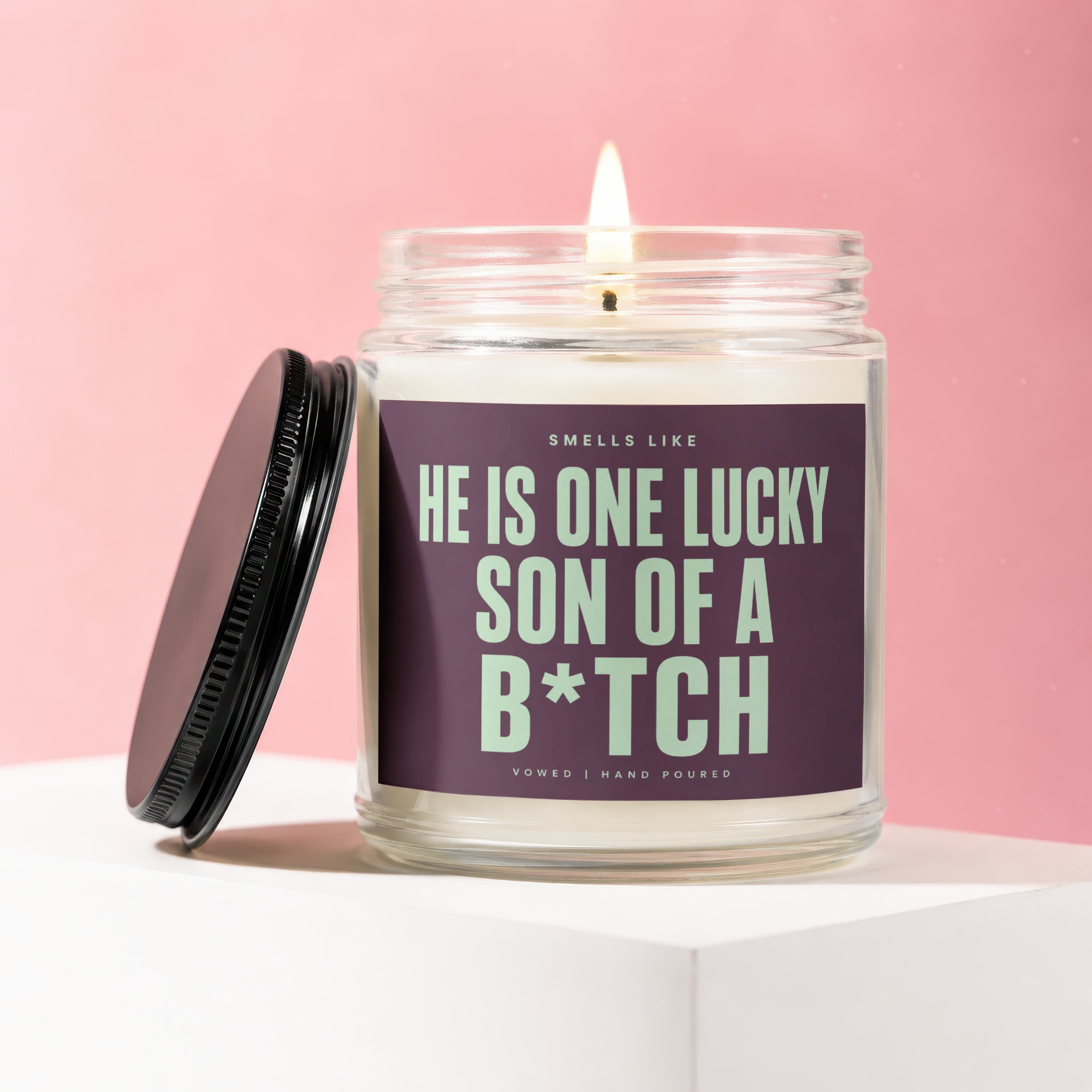 Candle with a lit wick and label reading "He is one lucky son of a b*tch".