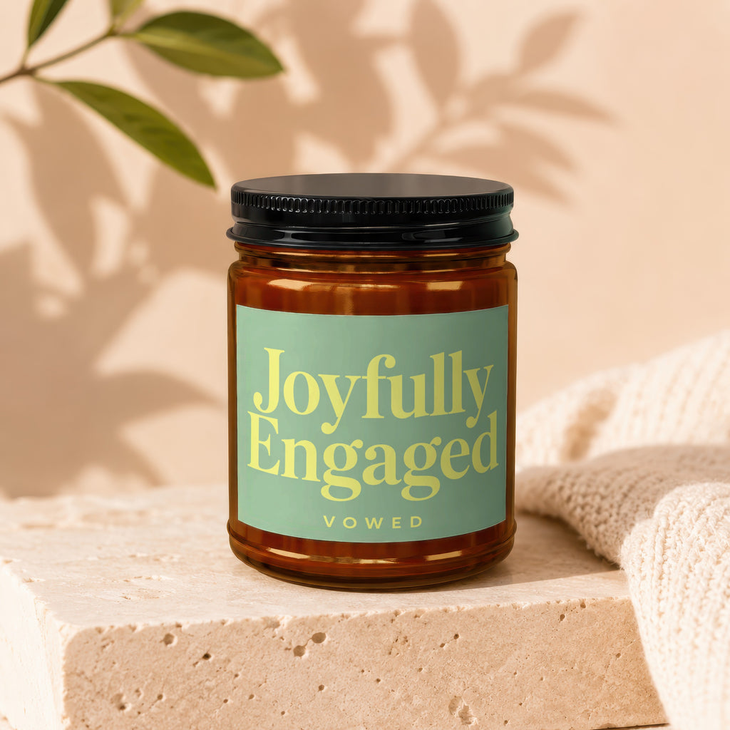 Brown glass candle with a light green label that reads "Joyfully Engaged Vowed".