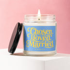 Scented candle with text "Chosen, Loved, Married, Vowed" on a blue label.
