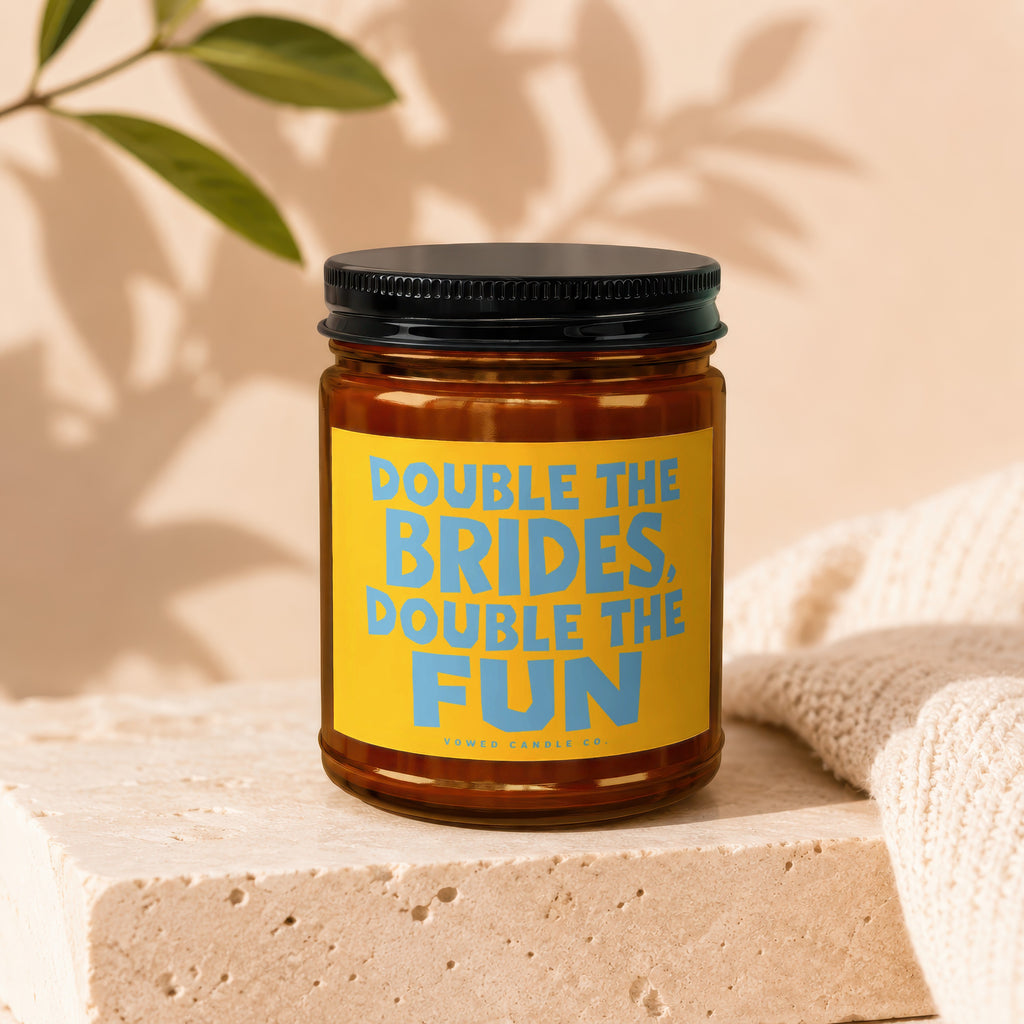 Brown glass candle in amber jar with a yellow label reading "Double the Brides, Double the Fun".