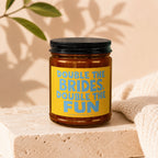 Brown glass candle in amber jar with a yellow label reading "Double the Brides, Double the Fun".