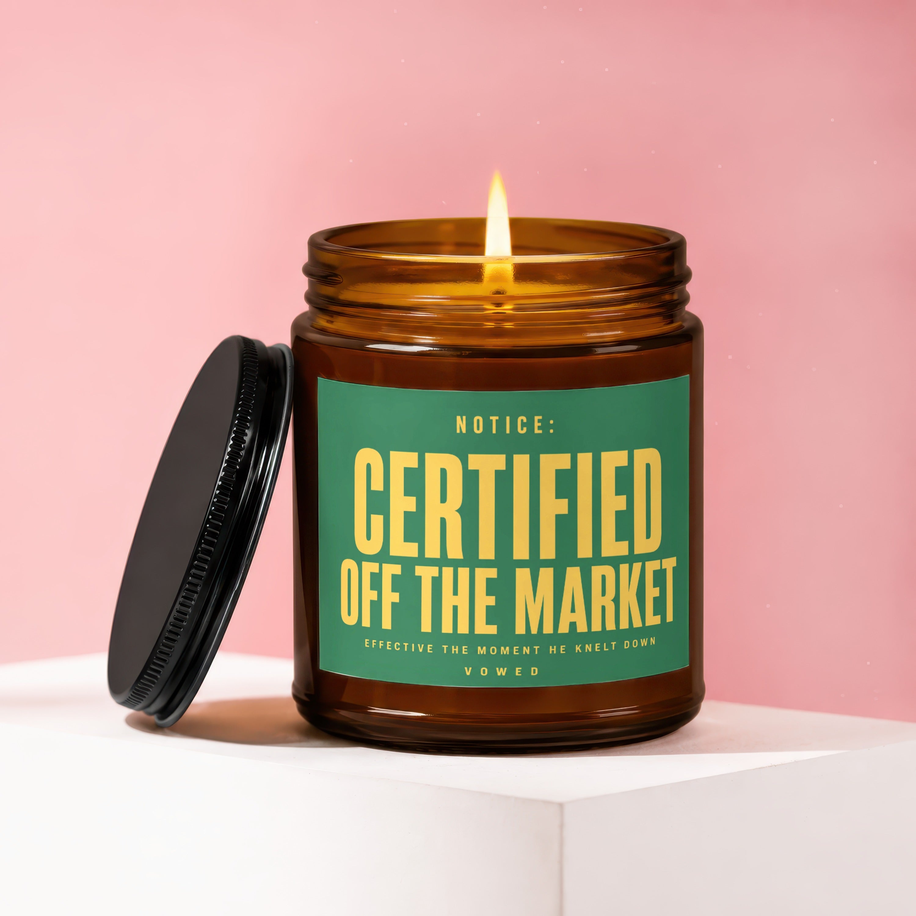 Amber jar candle with a lit flame, and a black lid beside it.