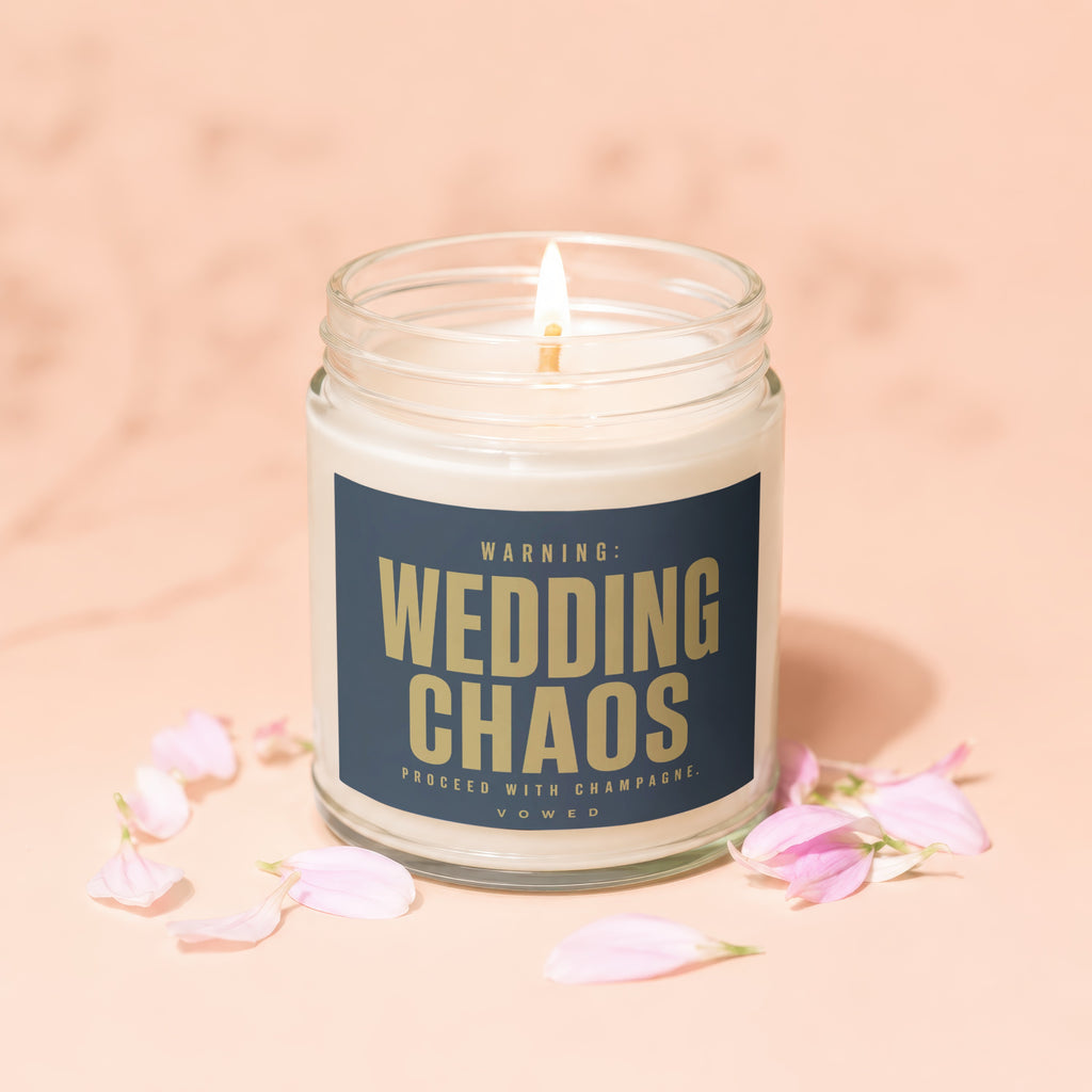 Jar candle with "WARNING: WEDDING CHAOS PROCEED WITH CHAMPAGNE." text, lit wick.