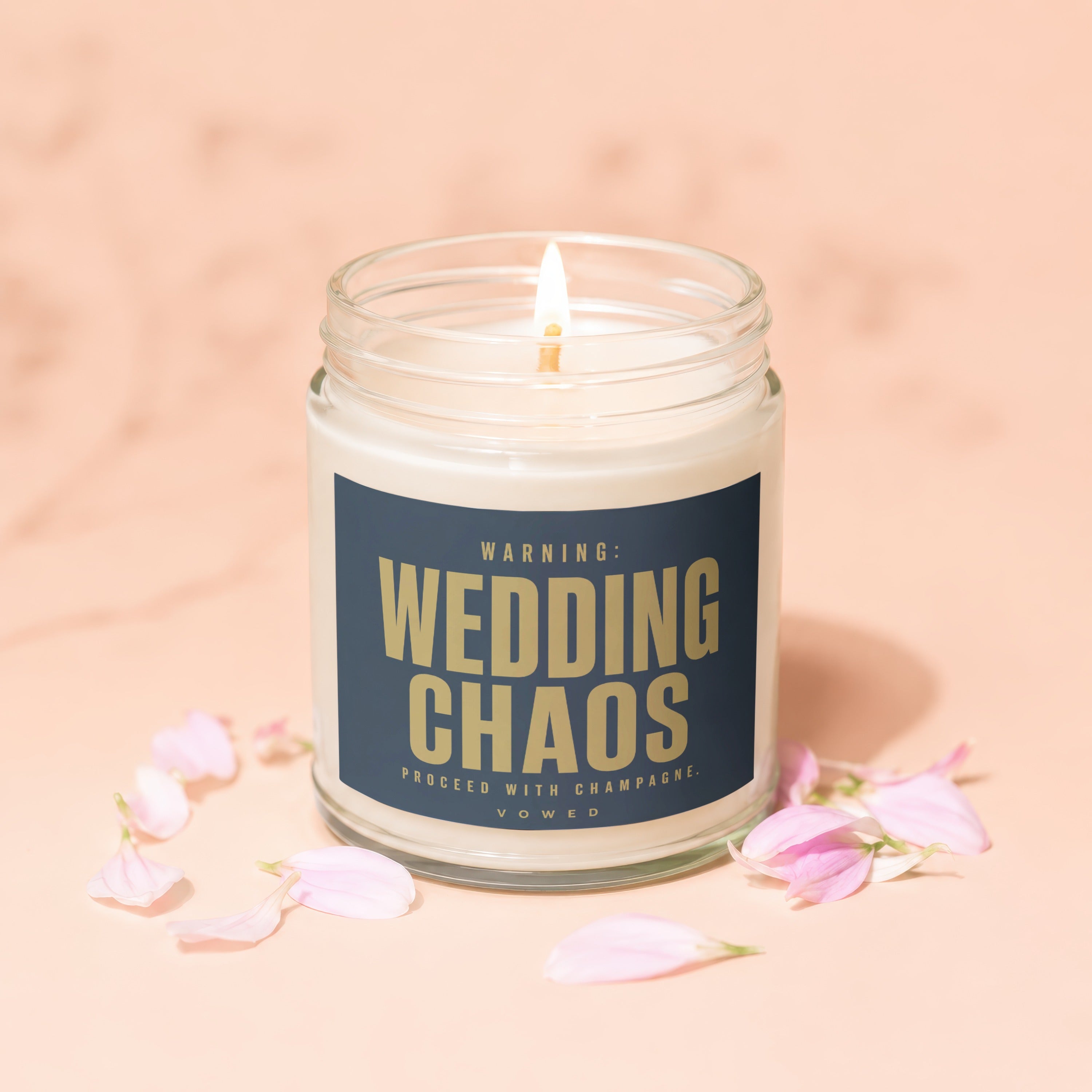 Jar candle with "WARNING: WEDDING CHAOS PROCEED WITH CHAMPAGNE." text, lit wick.
