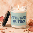 Candle with label "Smells Like Officiant Duties Vowed" burning with dried leaves.