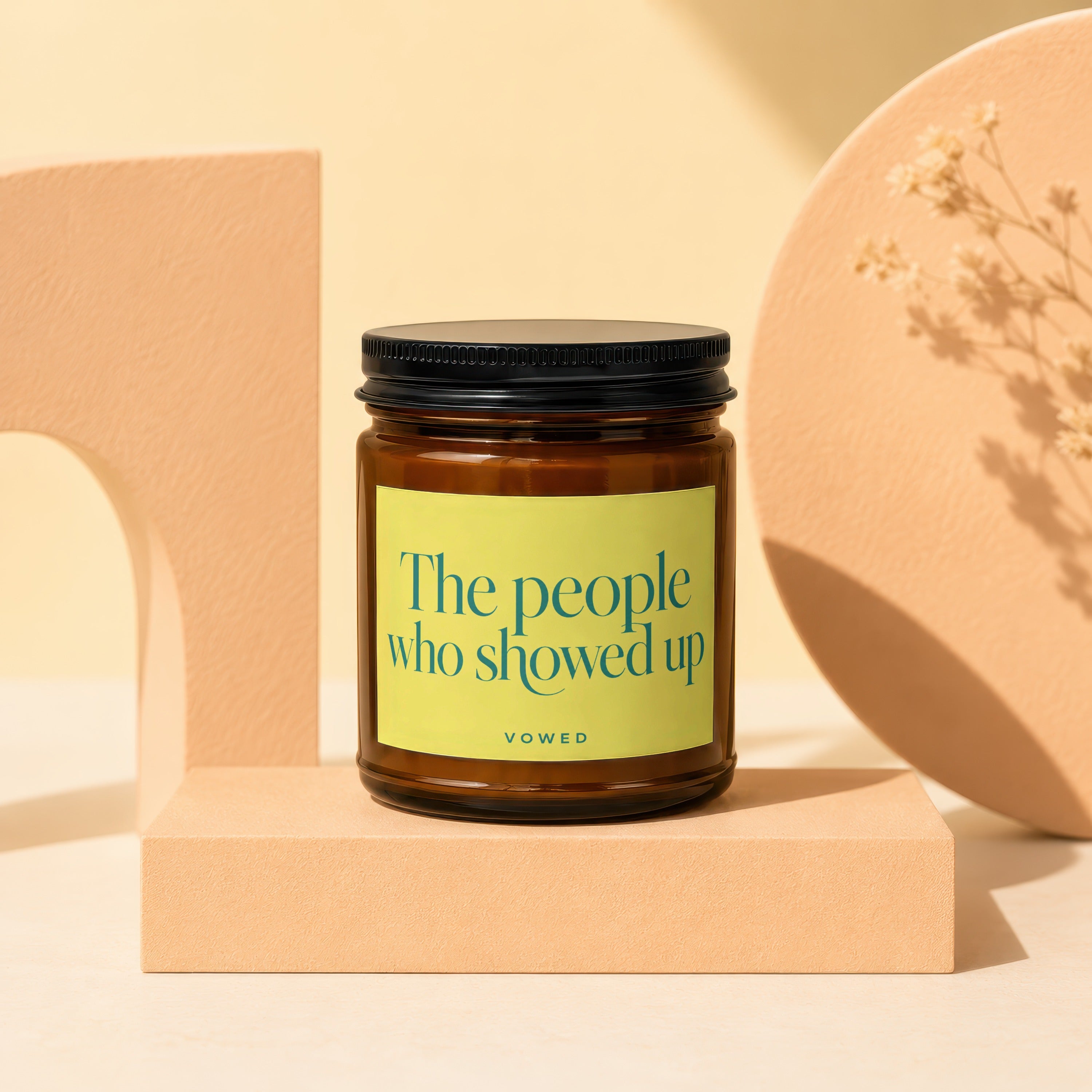 Amber candle with yellow label reading "The people who showed up VOWED".
