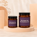 Two amber glass candles with purple labels read "The Group Chat Has Not Recovered."