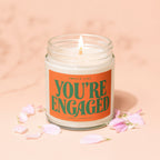 Jar candle with orange label reading "Smells Like You're Engaged" with Vowed Candle Co.