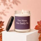 Candle with "Two Moms. One Lucky Me." text on label, lid off.