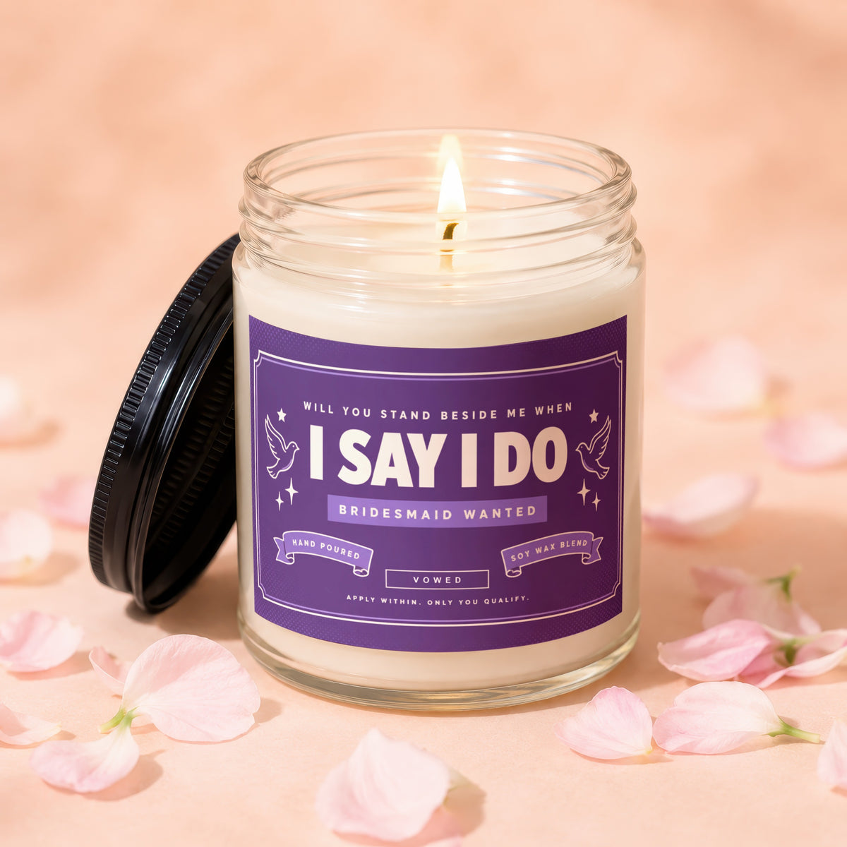 Candle with "I Say I Do Bridesmaid Wanted" label and lit wick.