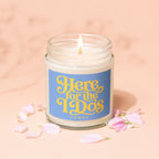 Glass candle with lit wick, reads "Here for the IDs VOWED" on a blue label.
