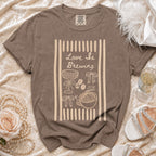 Brown comfort colors t-shirt with "Love Is Brewing" and coffee graphics.
